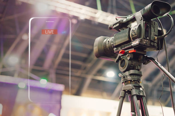 Professional video camera on a tripod beside a live streaming display